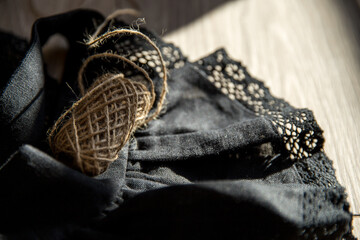 Details of vintage linen black dress. Woman linen dress on the floor with  ball of thread. Handmade with love for everyone. Image with selective focus and noise effect.