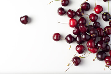 Obraz na płótnie Canvas Cherry on white table. Juicy ripe red berries of a sweet cherry on a white field. Contrast flat lay of cherries on a white background.