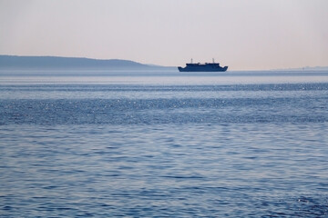 Sunlight reflecting in the sea, ferry boat in the background. Selective focus.