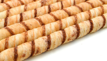 Heap of striped wafer tubules with the chocolate creamon background