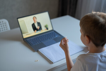 A boy learns the alphabet with a laptop teacher. Distance learning by video conference. Remote preschool education.