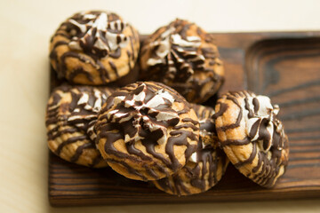 Sandy chocolate unusual striped cookies with marshmallows on a wooden plate tray. Cookies decorated with chocolate.