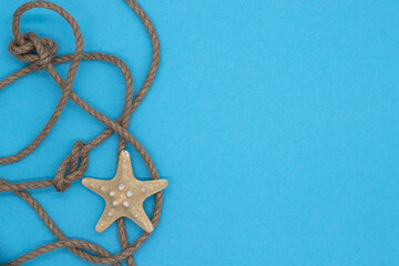 Fototapeta na wymiar Summer nautical composition, starfish and knot woven from a rope on blue background