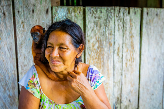 Woman and her rescued monkey at a local village on the Amazon River, Peru