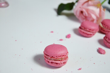 pink cake macaron, clean and flower pink rose on white table from above. Female working desk. Cozy breakfast. Flat lay style.