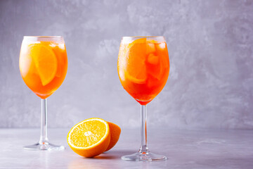 Aperol spritz cocktail on a gray background. Two glasses of aperol spritz with orange slised. Summer italian cocktail in glass. Copy space