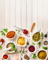 Different indian spices in a bowls and herbs on white wooden background. Top view of indian spices with copy space.