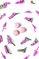 lady morning with macaroons and mauve flowers white desk background top view pattern