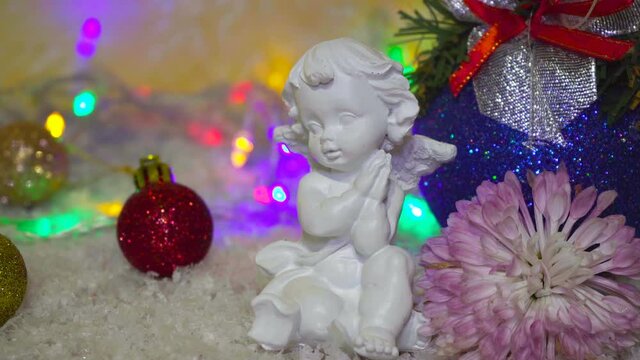 white christmas angel,little angel with folded arms in the snow in garlands background