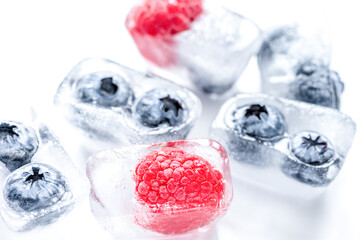Ice cubes with frozen berries on white background