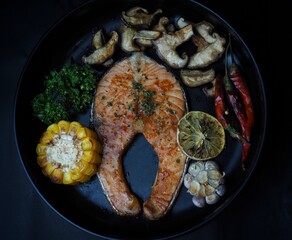 Delicious Grilled Salmon with thyme, garlic and lemon slices,shiitake mushroom on background.