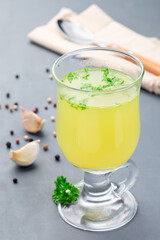 Chicken broth in glass with chopped parsley, vertical