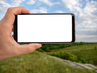 Hand holding smart phone with blurred backgroung. Blank screen for montage. Mockup image.