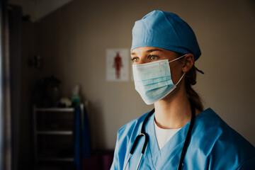 Fototapeta na wymiar Close up of young female caucasian nurse in scrubs with medical mask 
