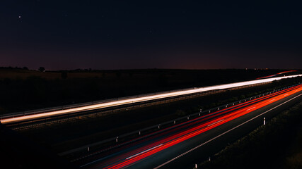 Fototapeta na wymiar Car light trails on a straight road under starry sky