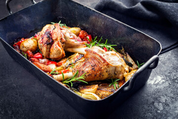 Traditionelle geschmorte Lammhaxen mit Aubergine, Kartoffel und Tomaten angeboten als close-up in einer rustikalen alten Bratpfanne