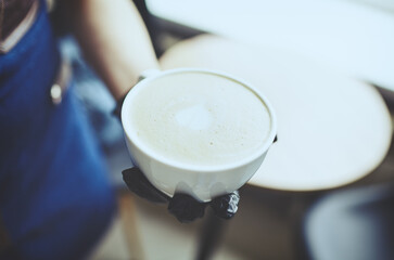 Barista wearing medical latex black gloves, making cappuccino, bartender preparing coffee drink. Blurred image, selective focus