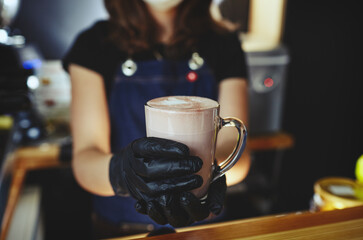 Barista wearing medical latex black gloves, making pink matcha latte with milk.Bartender preparing tasty drink.Blurred image,selective focus