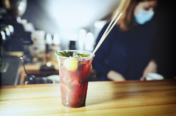 Bartender wearing face protection mask,making mojito cocktail. Process of bartending in bar.Mint leaves,ice,lime - ingredients for drinks in nightclub.Blurred image, selective focus