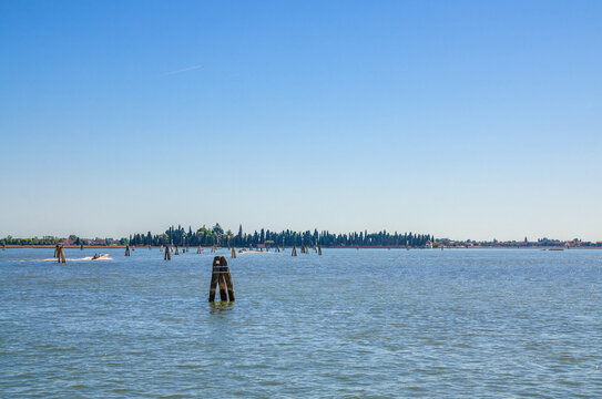 Panoramic view of San Francesco del Deserto island in Venetian Lagoon water with wooden poles. View from Burano island. Venice Province, Veneto Region, Northern Italy