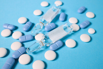 scattered pills and ampoules. on a blue background. virus protection concept. vitamins. injections