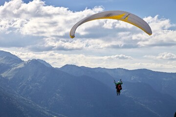 Paragliding among the mountains on sunny summer day. Paraglider flight against beautiful mountains...