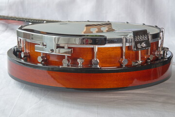 Ein Banjo Korpus aus rotem Holz und viele Schrauben, Knöpfe und Rand aus Metal liegt auf einem...