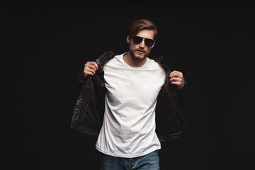 Fashion man, Handsome serious beauty male model portrait wear sunglasses and leather jacket, young guy over black background