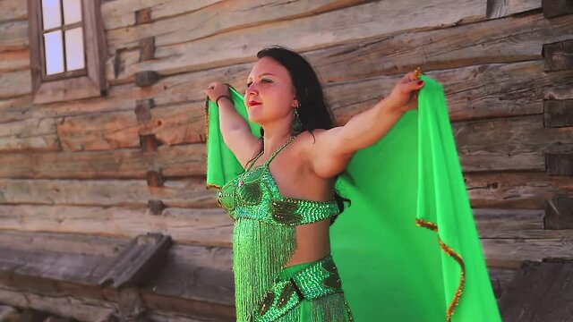 Jewish woman in a suit for belly dancing on a stone fluttering shawl in nature