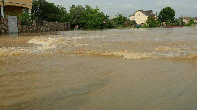 Couple trying to get into flooded home. Evacuated from house in small rubber boat. During flood largest weather disaster. City residents row through overflowing water street as tens, worst flooding.