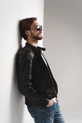 Obraz premium Fashion man, Handsome serious beauty male model portrait wear sunglasses and leather jacket, young guy over white background