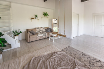 Fototapeta premium Luxury bedroom design in a rustic cottage in a minimalist style. white walls, panoramic windows, wooden elements of decoration on the ceiling, rope swings in the middle of a spacious room