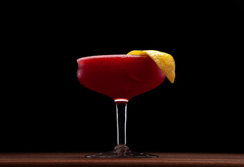 Cherry gin sour with a lemon peel in a vintage coupe glass