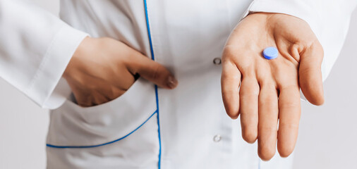 Doctor gives a pill in his hand. The nurse gives a dose of the drug for health.