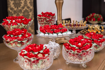 Várias vasilhas de vidro com doces confeitados em buffet em evento.