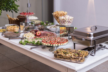 Vários tipos de alimentos em vasilhas sobre mesa de buffet.