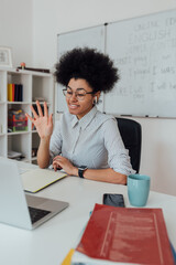 Young cheerful afro american woman, female teacher looking at computer screen and waving, giving...