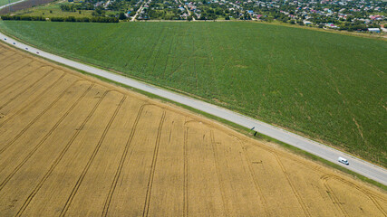 Aerial view of highway road between meadow and agricultural field.
