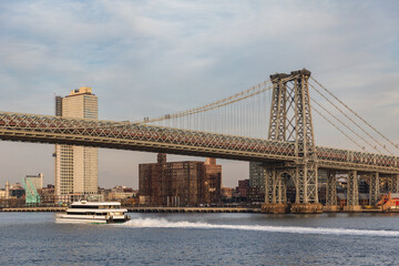 Obraz premium tall suspension bridge in a city on a sunset in summer with a boat under