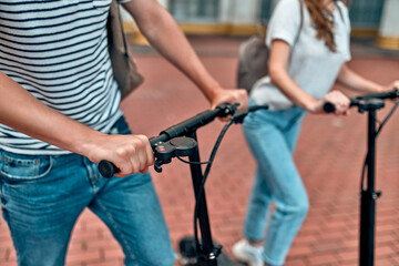 Cropped image of A charming girl and an attractive guy on electric scooters. A couple of students on scooters near the campus.