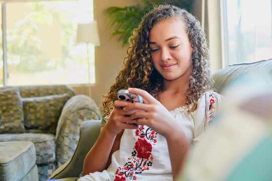 Mixed race girl using cell phone on sofa