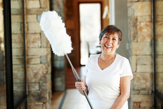 Smiling Hispanic woman holding duster