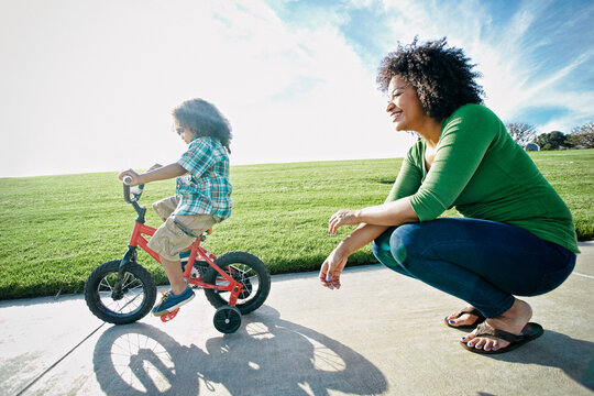Mixed race mother watching son ride bicycle