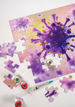 Studio shot of puzzle with Coronavirus model and vaccine vials and syringe