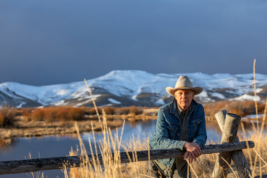 USA, Idaho, Sun Valley, Senior man in cowboy hat leaning against fence