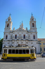 Vintage yellow tram and the Estrela Basilica (or Royal Basilica and Convent of the Most Sacred Heart of Jesus), in Lisbon, Portugal
