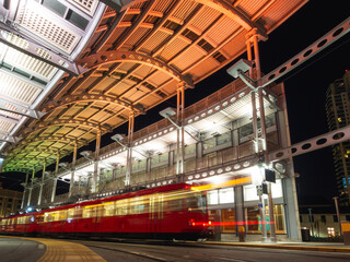 red train at a train station at night with orange lights on the roof