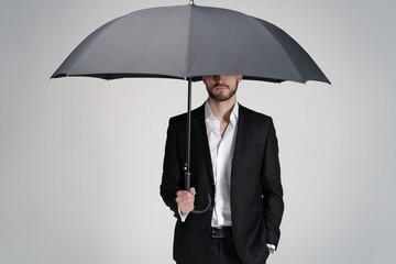 Businessman in a suit standing under black umbrella