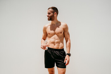 Barechested male athlete holding a bottle of water