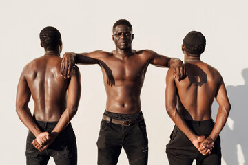 Black man leaning on friends, crossing hands behind their backs